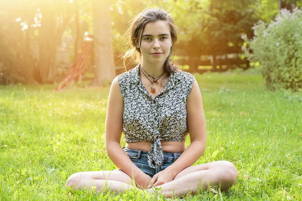 Beautiful teenage girl sitting on a meadow — Stock Photo, Image
