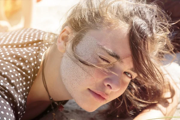 Mulher deitada na praia com areia no rosto — Fotografia de Stock