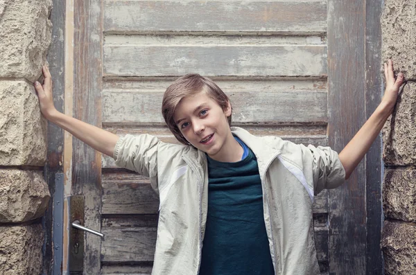 Portret van een lachende jongen staan tegenover een oude ingang — Stockfoto