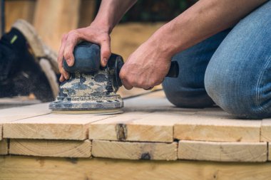 Öğütücüyle kereste zımparalayan bir işçiye yaklaş.