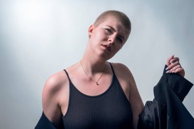 studio shot of a young, cool, strong woman with very short blond hair