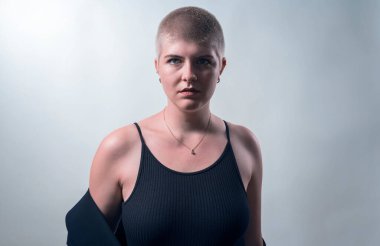 studio shot of a young, strong woman with very short blond hair
