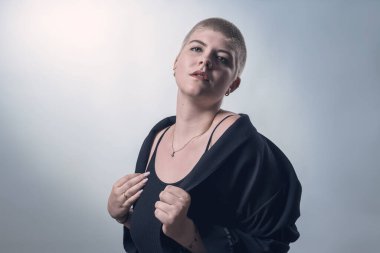 studio shot of a young, strong woman with very short blond hair in black clothes
