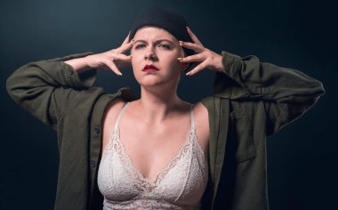 Kafasını büstiyer gibi tutan ciddi bir genç kadının stüdyo portresi.