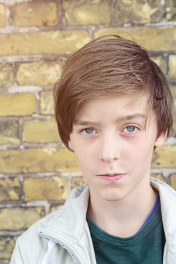 bir tuğla duvar önünde bir genç çocuk portresi