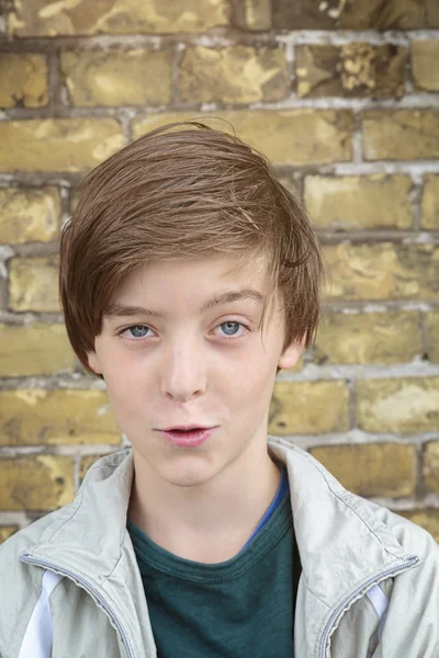 Portrait of a smiling teenager boy in front of a brick wall — Stock Photo, Image