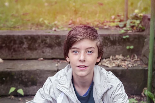 Uśmiechnięty chłopiec nastolatek, siedząc na schodach w parku — Zdjęcie stockowe