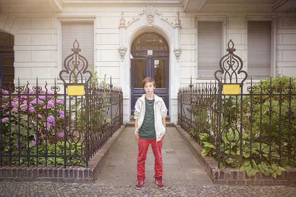 Teenager boy standing in an entrance with ornate metal fence — Stock Photo, Image