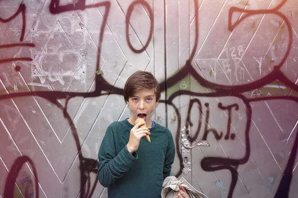 Adolescente menino na frente de um graffiti grande está comendo seu sorvete — Fotografia de Stock