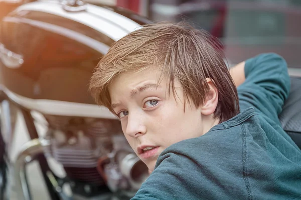 Cool tiener jongen is leunend tegen een motorfiets — Stockfoto