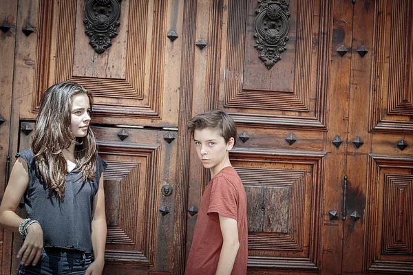Retrato de dos adolescentes frente a una enorme puerta de madera antigua — Foto de Stock
