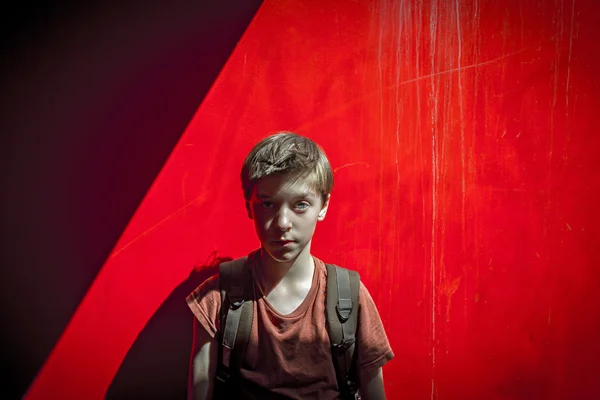 Portrait of a teenager boy with rucksack in front of a red wall, — Stock Photo, Image