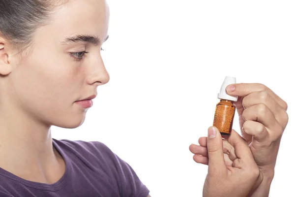 Vrouw is het onderzoeken van een fles van homeopathische geneeskunde, geïsoleerd op w — Stockfoto