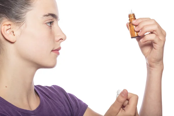 Woman is examine a bottle of homeopathic medicine, isolated on w — Stock Photo, Image