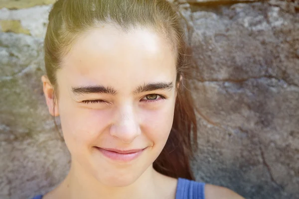 Portrait of a smiling teenage girl squinting one eye — Stock Photo, Image