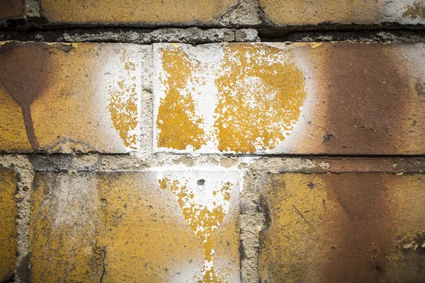 Faded white heart symbol on a grungy yellow brick wall — Stock Photo, Image