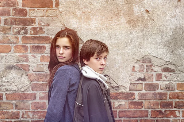 kardeşler bir eski tuğla duvarın önünde arkaya