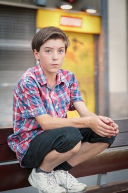 bir kenarda çömelmiş genç çocuk