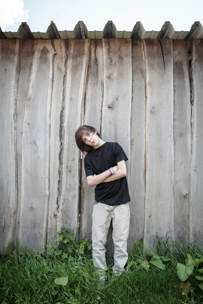 Oblicuo adolescente de pie frente a una pared de madera — Foto de Stock