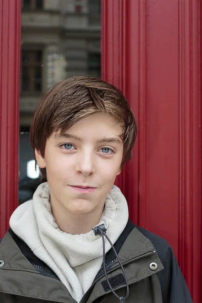 Retrato de um belo adolescente na frente de uma porta vermelha — Fotografia de Stock