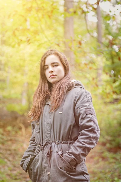 Portrait of a teenager girl with green parka in an autumn forest Stock Image