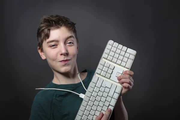 Adolescent souriant avec clavier d'ordinateur et fond gris f — Photo