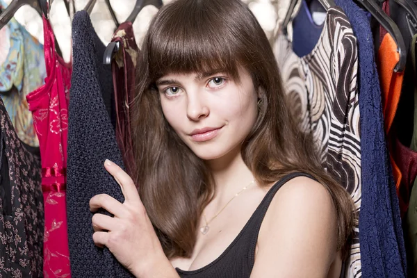 Retrato de uma bela adolescente na frente de alguns vestidos — Fotografia de Stock