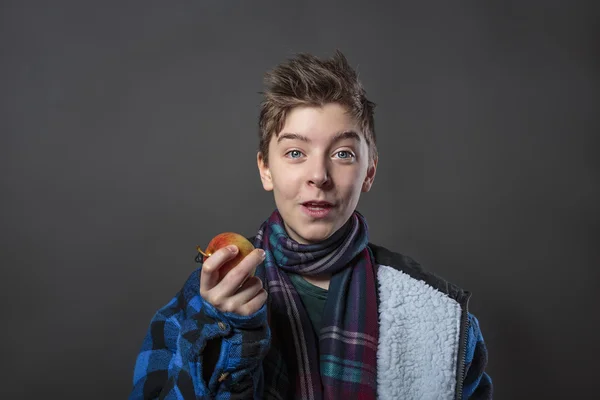 Funny teenage boy holding an apple, isolated on gray background — Stock Photo, Image