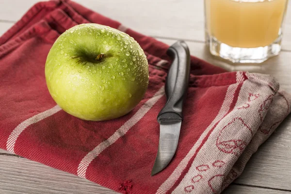 Натюрморт з мокрим зеленим яблуком на кухонному рушнику і ножем — стокове фото