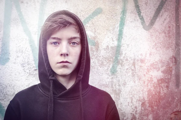 Egy tizenéves fiú előtt egy graffiti-s fekete kapucnis portréja — Stock Fotó