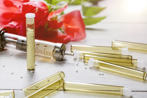 Small glass tubes with homeopathic medicine, syringe and flower — Stock Photo, Image