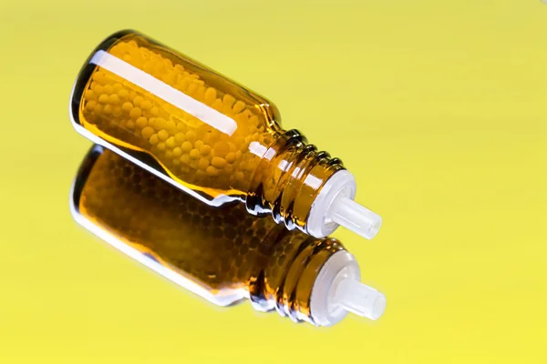 Flasche mit Homöopathie-Globuli auf einem Spiegel liegend — Stockfoto