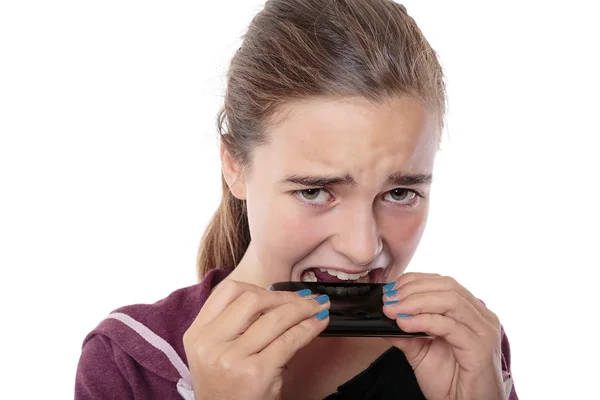 Desperate young woman bites in her smart phone, isolated on whit — Stock Photo, Image