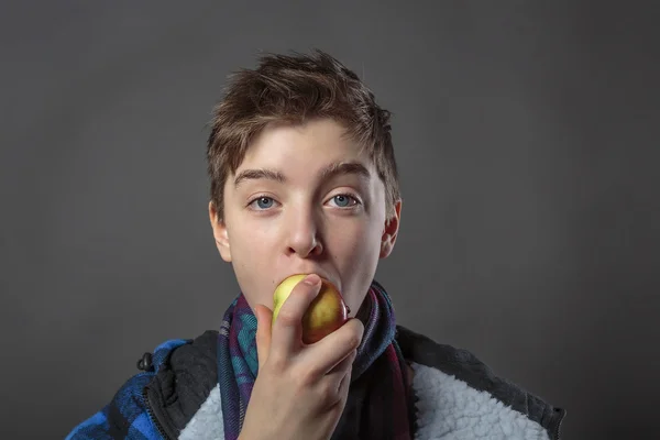 Retrato de un adolescente comiendo una manzana con chaqueta de invierno , — Foto de Stock