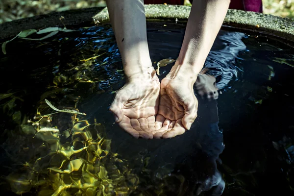 Aguantando el agua de un pozo en las manos ahuecadas Imagen de archivo