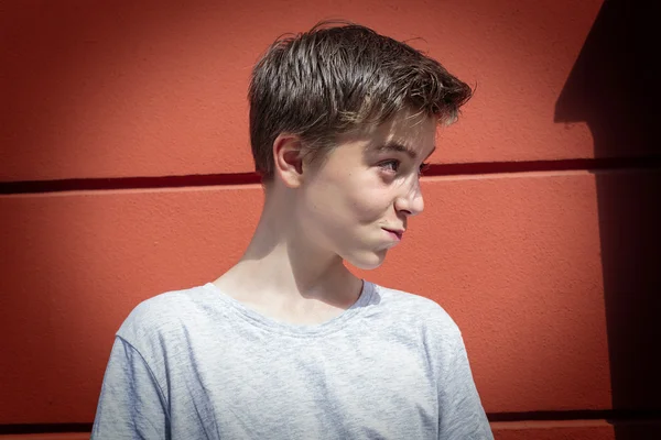 Retrato de un adolescente sonriente con pared roja — Foto de Stock