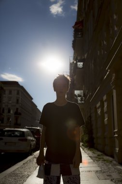 arkadan aydınlatmalı çekim bir cadde üstünde bir oğlan