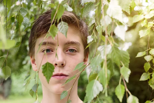 Porträt eines halbwüchsigen Jungen, versteckt hinter Blättern — Stockfoto