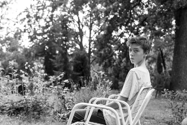 รูปภาพของเด็กชายวัยรุ่นนั่งบนเก้าอี้ — ภาพถ่ายสต็อก