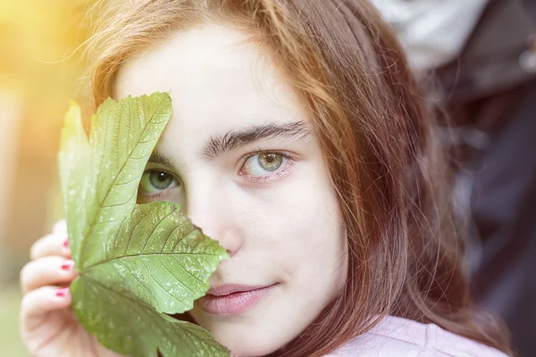 Teenager Mädchen mit einem Ahornblatt über dem Gesicht — Stockfoto