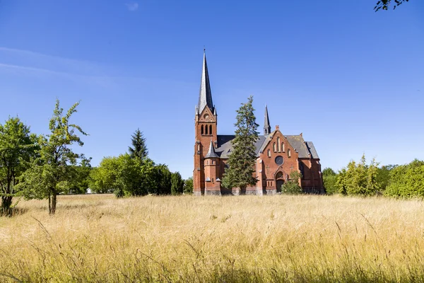 Igreja de tijolo vermelho em um prado selvagem — Fotografia de Stock