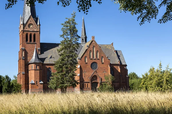 Kościół z czerwonej cegły na dzikiej łące — Zdjęcie stockowe