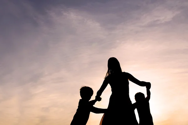 Silhouette de la mère et des enfants dansant au coucher du soleil — Photo