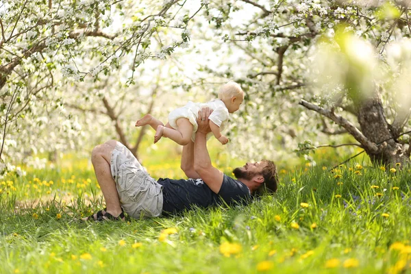 Père heureux soulevant bébé fille ludique dans la prairie — Photo