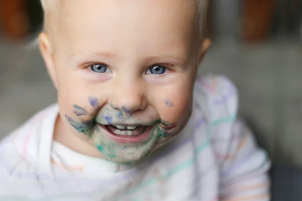 彼女の顔に乱雑な塗料で女の赤ちゃんを笑ってください。 — ストック写真