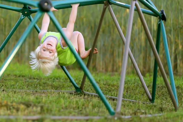 Petit enfant jouant à l'escalade de terrain de jeu sur des barres de singe — Photo