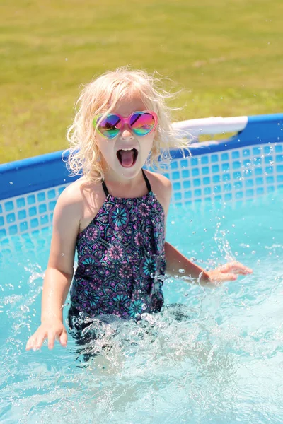 夏天的一天 一个可爱而快乐的小女孩在自家后院的游泳池里玩耍时 她兴奋地微笑着 — 图库照片