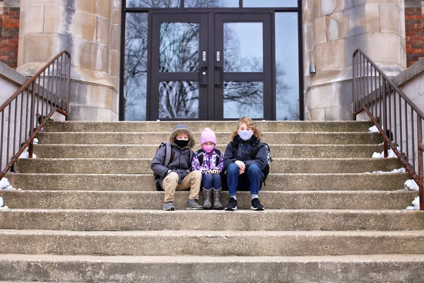 Drei Kleine Kinder Sitzen Auf Den Vorderen Stufen Ihres Grundschulgebäudes — Stockfoto