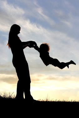 Günbatımında dışında çocuk ile oynarken annesi silüeti