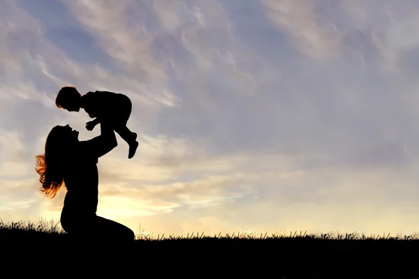 Silhouette di felice madre giocare fuori con bambino — Foto Stock